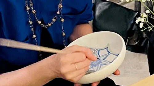 Person painting a design on a bowl.