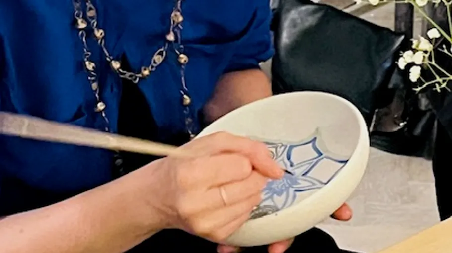 Person painting a design on a bowl.
