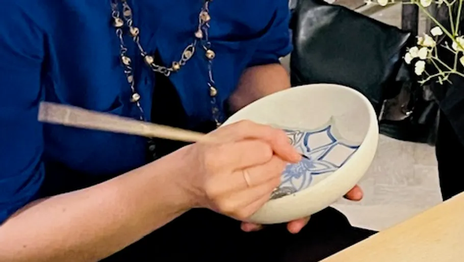 Person painting ceramic bowl indoors.