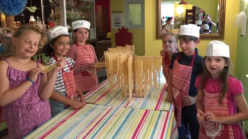 Children drying pasta on a striped table.
