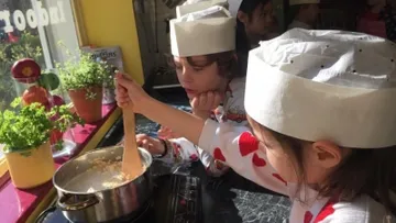 Children in chef hats cooking in kitchen.
