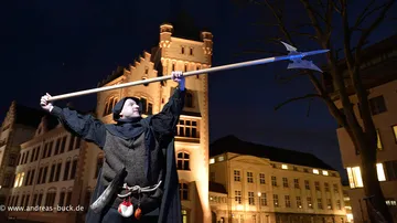 Person mit Speer im mittelalterlichen Kostüm, Nachtstadt.