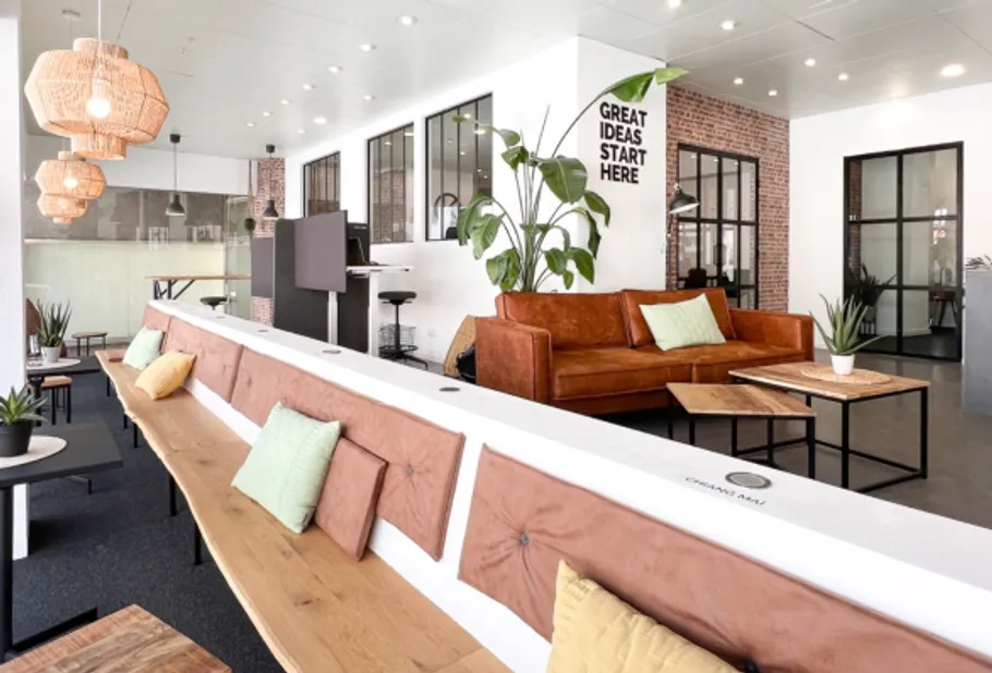 Modern office lounge with couches and plants.