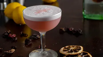 Rosa Cocktail mit Schaum auf Holztisch.