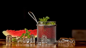 Mint in wire basket, ice, watermelon slice.