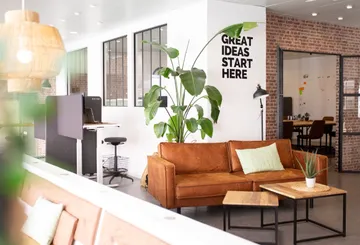 Office with couch, plant, motivational text.