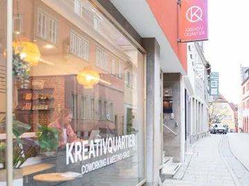 Straße mit Coworking Space und Fensterreflexionen.
