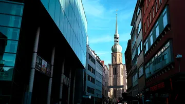 Kirchturm zwischen modernen Gebäuden.