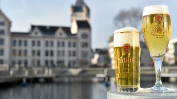 Zwei Biergläser vor historischem Gebäude.