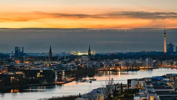 Stadtpanorama mit Sonnenuntergang und Fluss.
