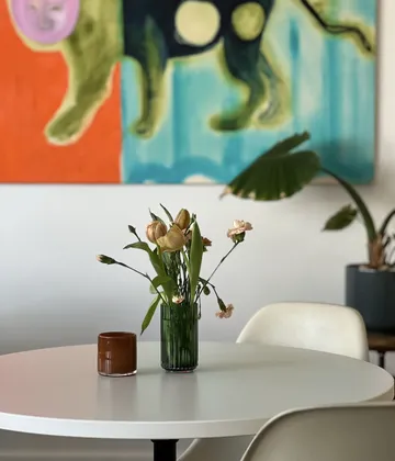 Flowers in vase on round table, artwork background.