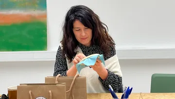Woman embroidering at a table with bags.