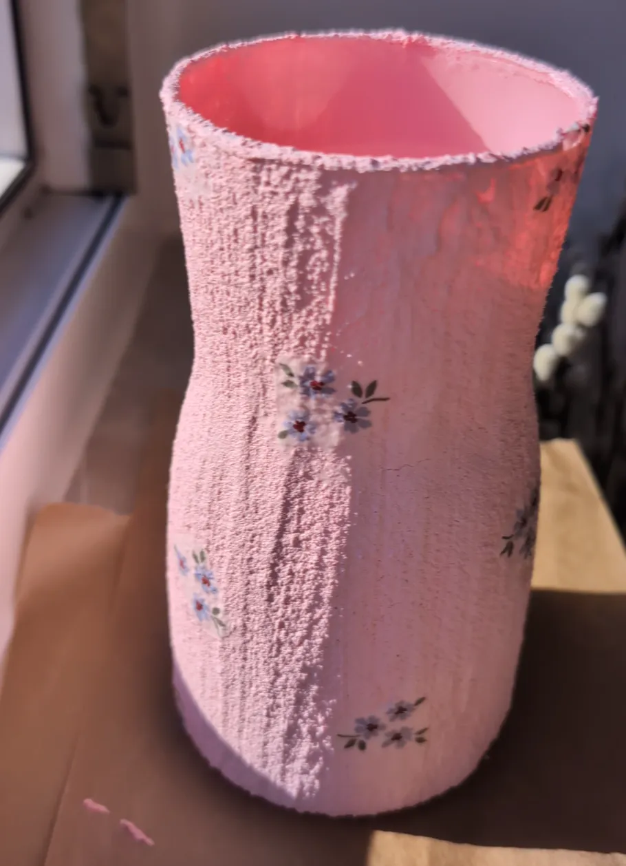 Rosa Vase mit Blumenmuster auf Fensterbank.