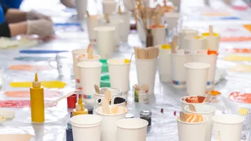 Cups with paint on a messy table.