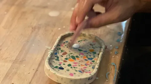 Hand fertigt ein buntes Terrazzo-Tablett.