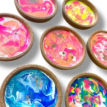 Colorful wax in round cork dishes on white.
