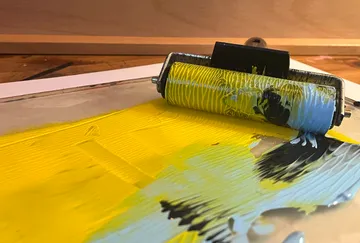 Farbrolle mischt gelbe und schwarze Farbe.