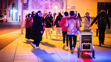 Gruppe mit Kopfhörern geht nachts spazieren.