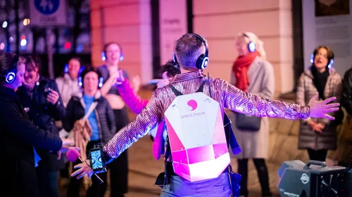Group with headphones dancing outdoors at night.