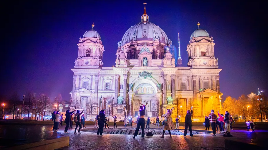 People dancing in front of a cathedral at night.