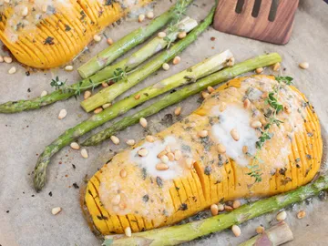 Hokkaido-Kürbis wird geröstet, umgeben von Spargel.