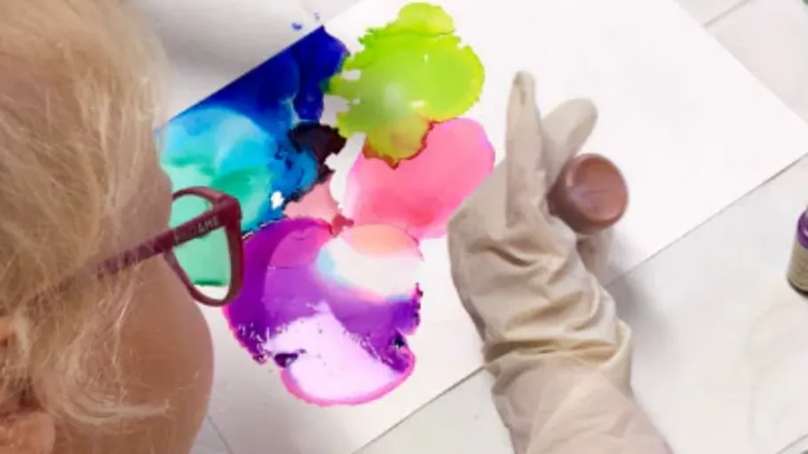Person painting colorful abstract art on paper.