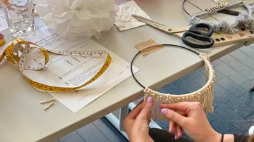 Hands crafting macrame on a table.