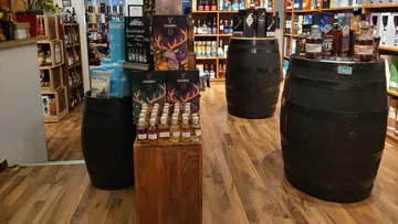 Liquor bottles displayed on wooden barrels in store.