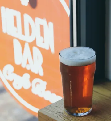 Pint of beer on table near Helden Bar sign.