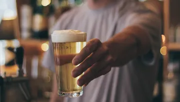 Person holding a beer glass in a bar.