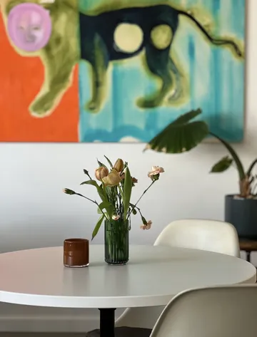 Flowers on table with abstract painting behind.
