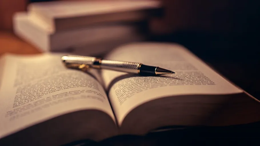 Open book with pen, dimly lit room.