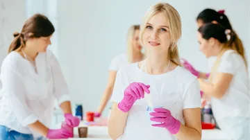Woman wearing gloves, mixing substances in a lab.