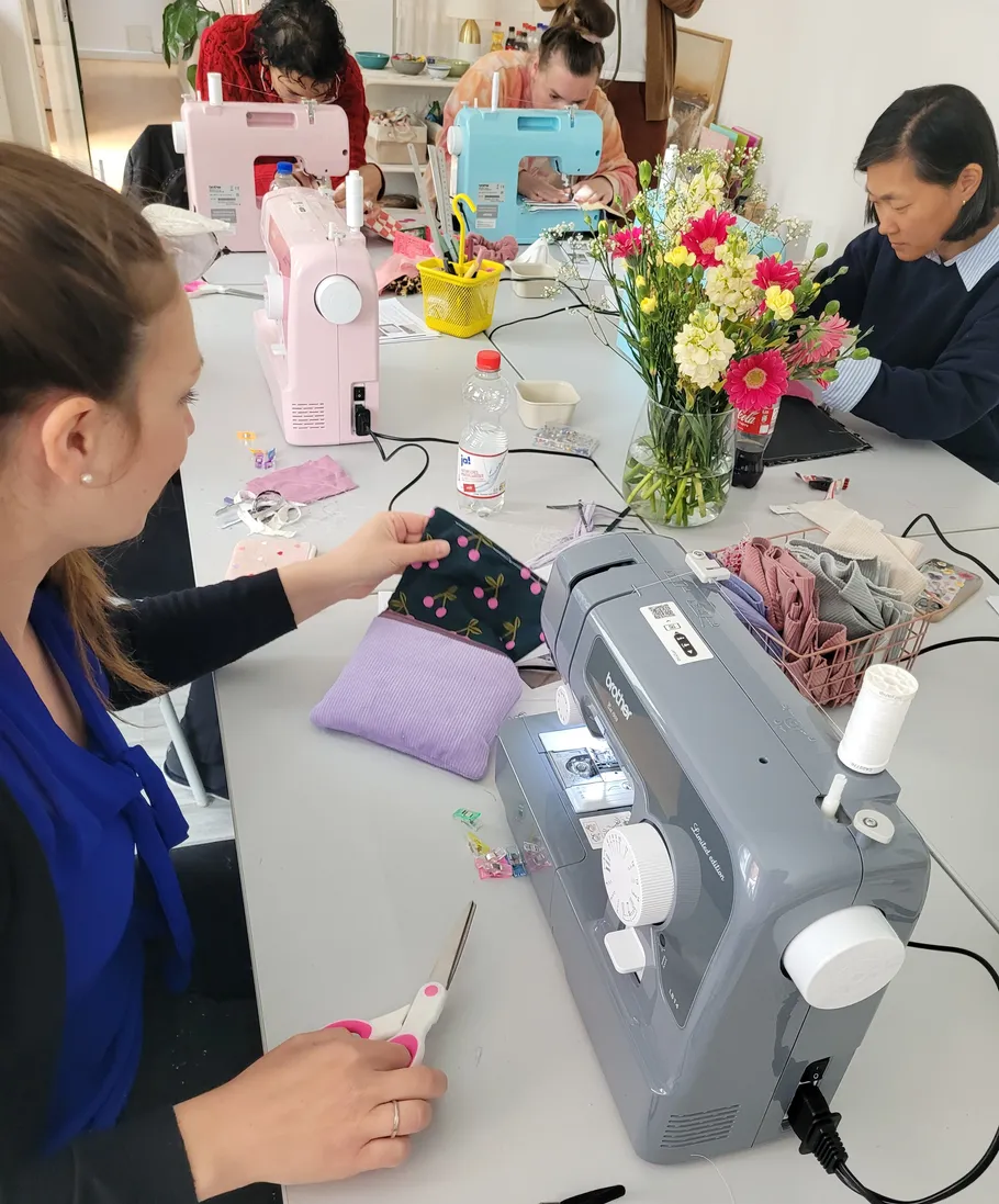 People sewing together at table workshop.