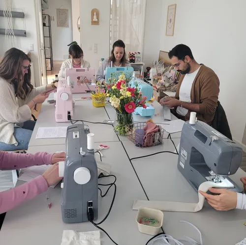Group sewing with machines around a table.