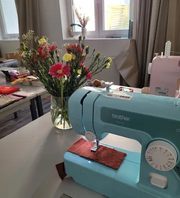Nähmaschine auf Tisch mit Blumen.