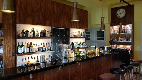 Bar with bottles and stools, wooden interior.