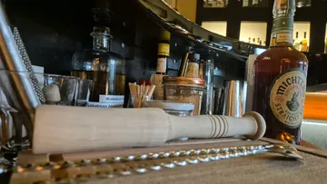 Barwerkzeuge und Whiskeyflasche auf Tresen.