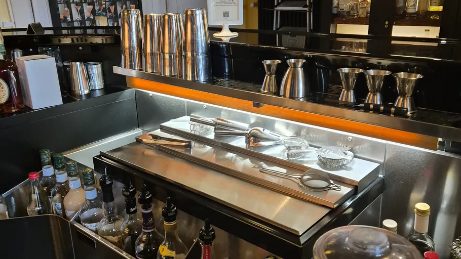 Bar counter with bottles and metal shakers.