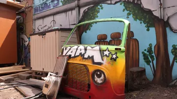 Car door with graffiti outdoors, colorful mural background.
