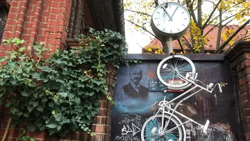 Bicycle on a graffiti wall with a clock.