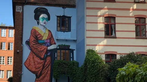 Großes Wandgemälde einer Frau an Gebäudewand.