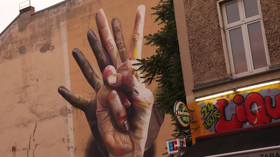 Mural of hands on building wall, urban setting.