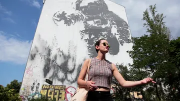 Woman poses with large astronaut mural outside.