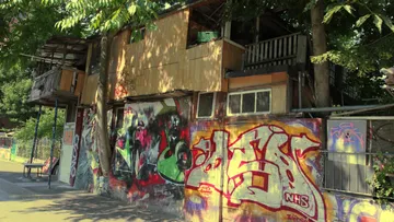 Wooden house with graffiti on concrete wall.