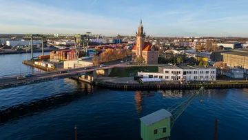 Hafen mit Turm, Brücke und Containern, tagsüber.
