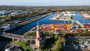 Container und Turm nahe Hafenbereich am Fluss.