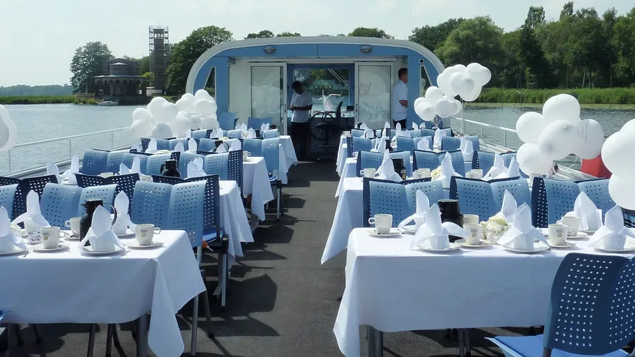 Tables set with white balloons on a boat.