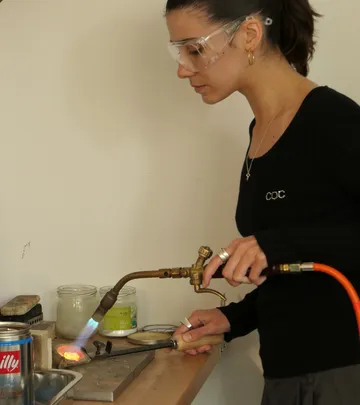 Frau benutzt Lötlampe in einer Werkstatt.