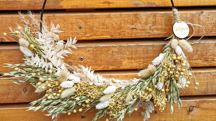 Dried flower wreath hanging on wooden wall.